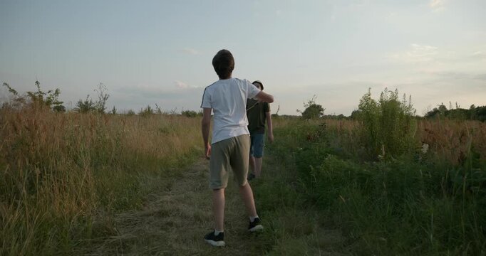 Two boys play badminton on nature. Teenagers spending time together. 4K 10-bit