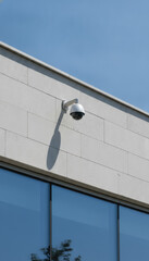 Obraz premium Dome security camera on modern building exterior with blue sky