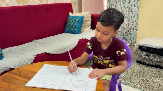 Young Child Completing Schoolwork At Home While Sitting At A Table