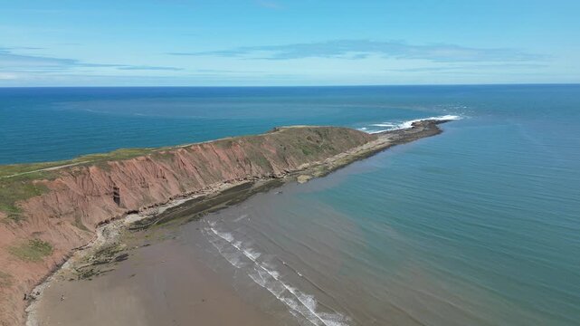 Aerial push in view of Filey Brigg peninsula and dramatic cliffs, North Yorkshire, England