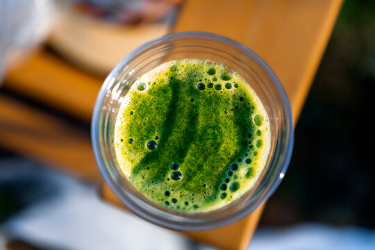 Top view of fresh green smoothie in plastic cup outdoors. Healthy raw diet and vegan detox nutrition.