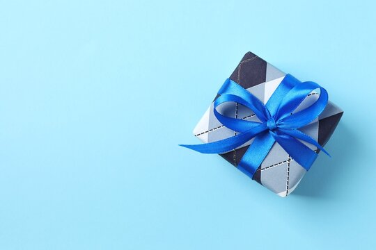 Beautiful gift box on blue background, top view with empty space