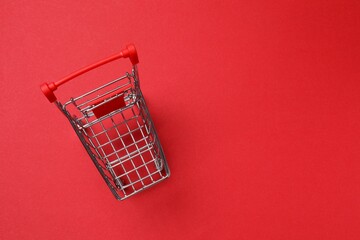 Photo of small silver shopping cart on red background, top view © Sunlight