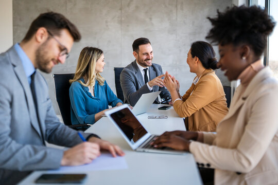 Multicultural professional businesspeople working together on research plan in boardroom.