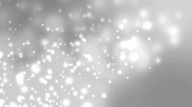 Glimmering white bokeh particles float and sparkle in soft focus abstract background.