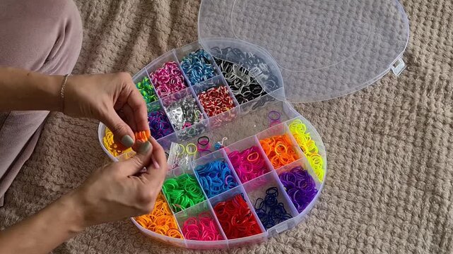 Organizing colorful rubber bands in a storage container on a carpet