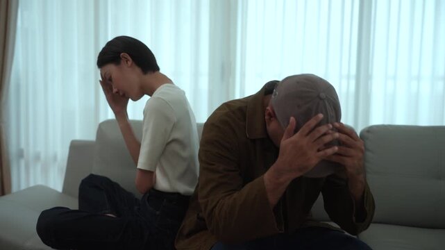 Heartbroken couple sitting apart after an unresolved family conflict at home. Relationship challenges, emotional stress. Communication breakdown, financial pressure. Mental wellbeing and marriage.
