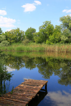 Rustic wooden pier extending into a calm lake surrounded by lush green trees