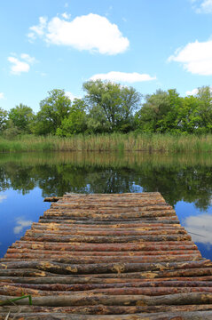 Wooden pier extending into a calm lake surrounded by lush green trees
