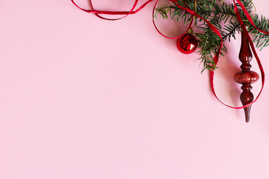 Christmas background. Elegant vintage glass finial ornament, red bauble and ribbon on fir branch on pastel pink background with copy space. Xmas flat lay