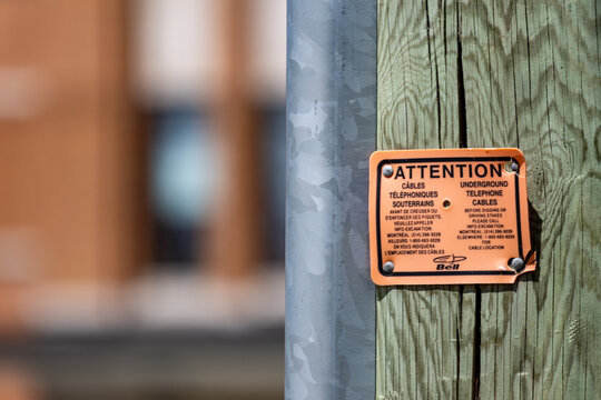 La Tuque, Quebec, 23 May 2026 : Orange warning sign from Bell attached to a wooden utility pole indicates underground telephone cables.