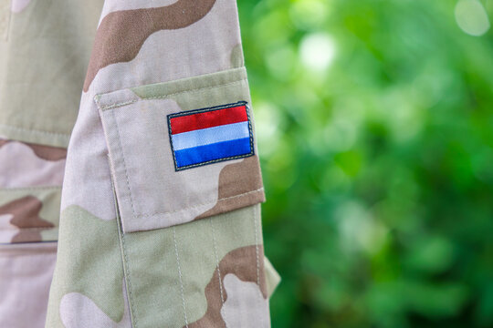 Dutch military uniform with flag of The Netherlands in front of a green background