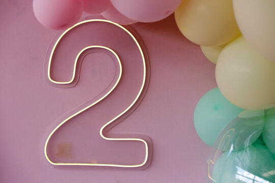 LED neon luminous sign in the shape of number two with colorful balloons