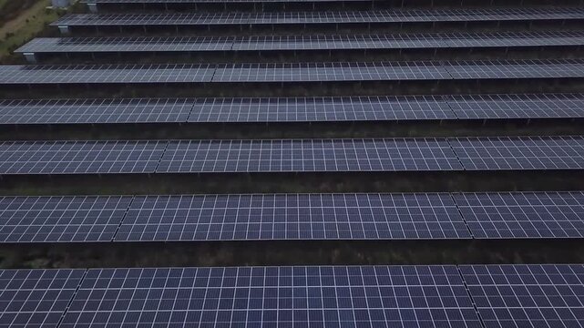 Short aerial drone clip showing strong horizontal lines of solar panel rows in Borger, Drenthe. On the left side of the frame, the transformer station with inverters and transformers is visible.