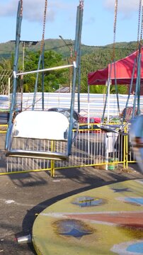 Vertical video of an empty swing ride moving at an outdoor fairground