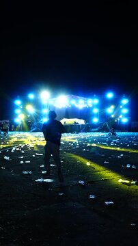 Vertical video of an empty outdoor concert area with bright blue stage lights