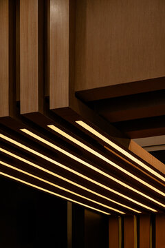 Angled wooden slatted ceiling design featuring warm linear LED lighting.