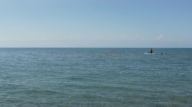 Slow motion of a person on a SUP board far away on the southern shore of Lake Issyk-Kul, Kyrgyzstan, 4K video