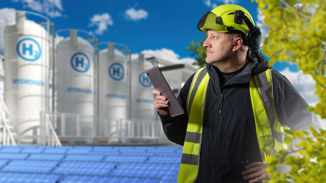 Hydrogen energy. Engineer monitors a green hydrogen production and storage facility powered by solar energy using a digital tablet.