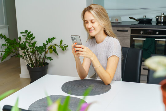 Young woman using smartphone while sitting at dining table at home