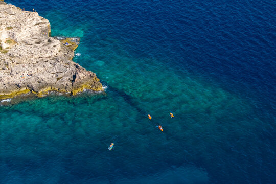 Top down view of colorful kayakers paddling across clear Adriatic waters near Pula Croatia