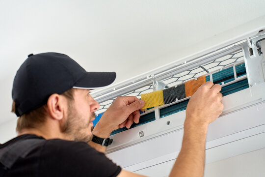 Man cleaning air conditioner filter