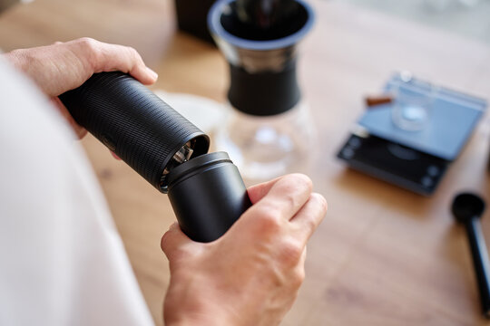 Hands opening hand coffee grinder