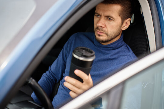 Man drinking coffee from reusable cup in car