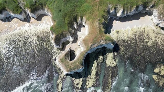 Aerial vertical rising view over rugged chalk cliffs and sea caves at Flamborough, England