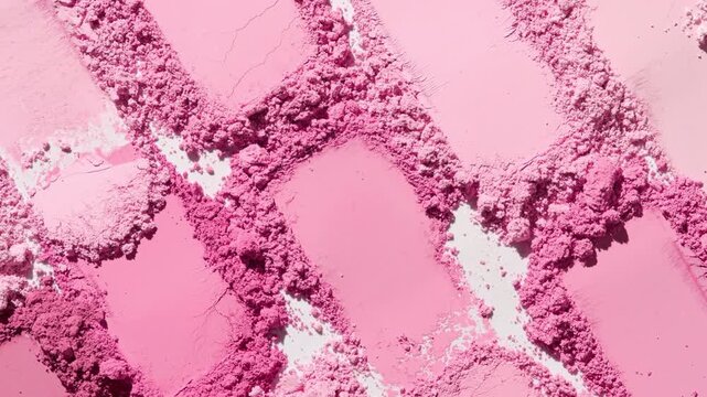 Top view high-magnification close-up of abundant pale to pink shades smeared powder heaps lit with orbiting light causing moving shadows