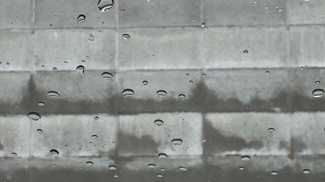 Accumulating Raindrops on Glass with Urban Concrete Block Wall Background
