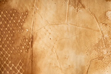 Fototapeta premium Old vintage paper texture. Warm brown aged paper with worn areas, stains, creases, irregular marks and faded imprints on the surface.