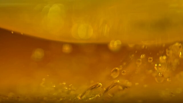 Golden oil contains suspended bubbles in a luminous macro view. Concept food advertising, cooking brands, packaging, banners and abstract design.