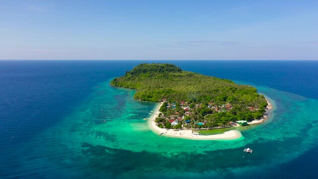 Himokilan Island, Leyte Island, Philippines. Tropical island with a village and a white beach. Turquoise water and coral reefs around the island. Summer holiday vacation concept.