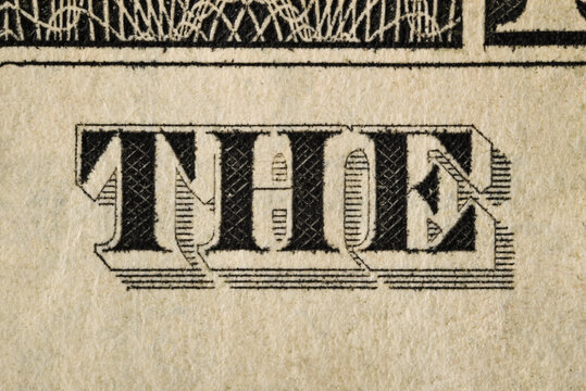 Macro detail of a one-dollar banknote. Engraved lettering, fine linework and aged paper texture visible in close-up.
