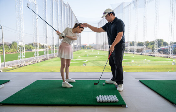 Golf Coach Guiding a Female Golfer's Backswing and Body Position During a Private Lesson at an Outdoor Driving Range