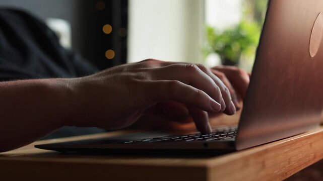Close-up of hands typing on a laptop keyboard in a well-lit room