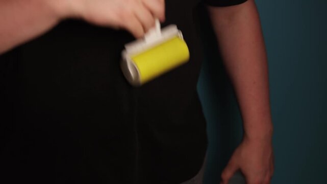 Person using a lint roller to clean clothing for a fresh appearance