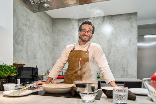 Happy man cooking healthy meal in modern kitchen