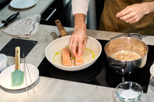 Chef preparing salmon fillets on a cooking pan
