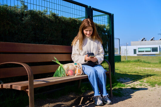 Mature woman using smartphone on park bench