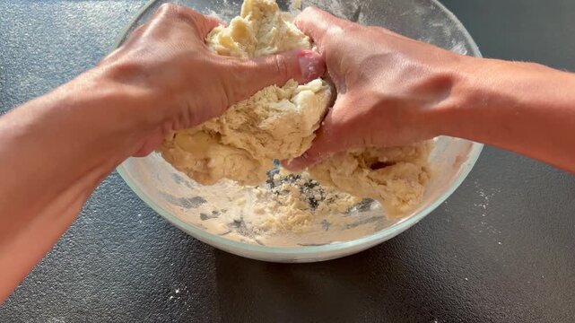 A woman kneads dough with her hands. The hands-on process of baking