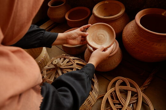 Person holding handmade clay pottery craft at traditional artisan market display