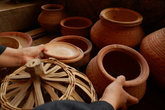 Person holding traditional brown clay pottery craft at local workshop display
