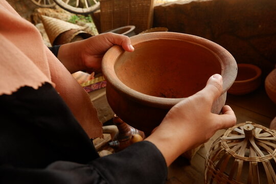 Close-up of tourist hands holding handmade earthenware vessel at local craft shop