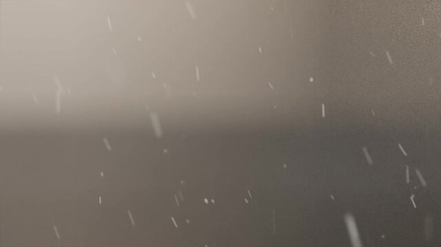 Falling bright particles entering frame and drifting downward by glass pane, blurred two-tone plane
