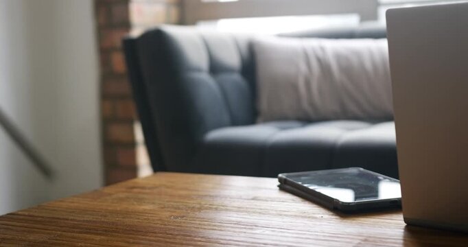 Silver laptop is sliding in from right, touchscreen device is resting on wooden table for work