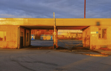 Industrial gatehouse with covered driveway and metal canopy in warm dusk sunlight © ossyffer