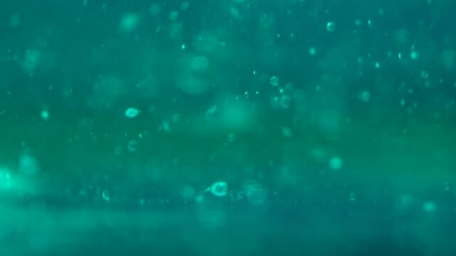 Macro view of oil bubbles suspended in a glowing blue liquid with soft highlights and texture. Concept abstract background, food ingredient, cosmetic fluid, branding, packaging and creative design.