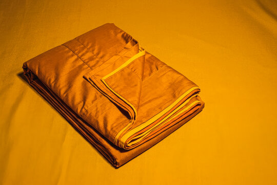 Folded saffron monk robe on yellow fabric